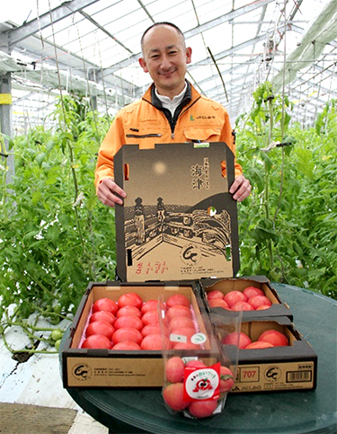 「『桃太郎』は当地に欠かせない品種」と臼井さん。昨シーズンにデザインを一新した出荷箱を手に。